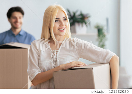 Husband And Wife Carrying Moving Boxes Into New Flat Or House Changing Apartment. Selective Focus 121382020
