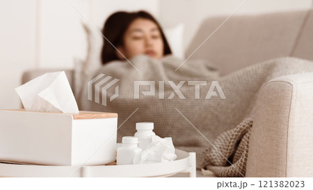 Sick Asian Woman Sleeping with High Fever and Medicine on Foreground 121382023