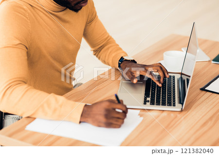 Doing Research. Unrecognizable black businessman working on laptop, browsing information and writing report, free space 121382040