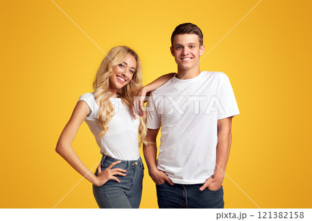 Cool millennials. Smiling guy and girl posing over yellow background, copy space Cool millennials. Smiling guy and girl posing over yellow background, copy space 121382158