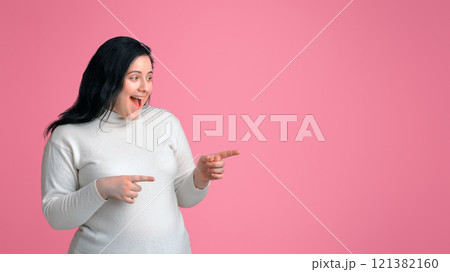 Look There. Surprised Plump Woman Pointing Aside At Copy Space On Pink Background With Both Hands, Indicating Great Offer 121382160