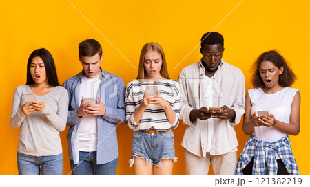 Problematic smartphone use. Multiracial group of teenagers using mobile phones over yellow background, panorama Problematic smartphone use. Multiracial group of teenagers using mobile phones over yellow background, panorama 121382219