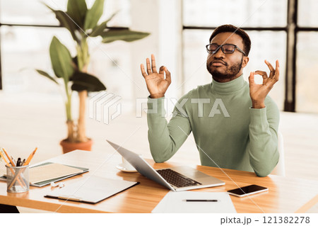 Relaxation At Work. Afro businessman meditating at work, dealing with stress and anxiety. Free space 121382278