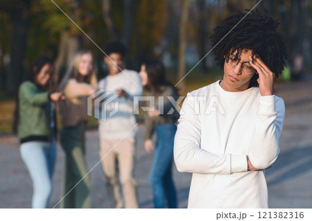 Multiracial group of teenagers pointing at frustrated black guy, spending time in park 121382316
