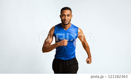 Running Competition. Confident black sportsman running, looking at camera, yellow background. Panorama, copyspace 121382363