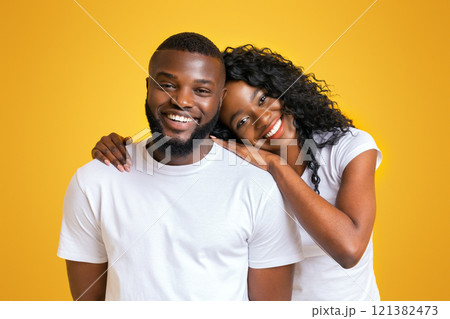 A man and woman are smiling while posing together against a yellow background. A man and woman are smiling while posing together against a yellow background. 121382473