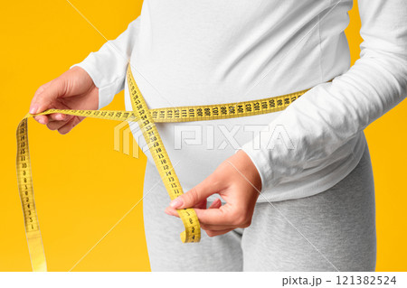 Unrecognizable Pregnant Lady Measuring Belly With Tape Standing Over Pink Studio Background. Cropped, Selective Focus Unrecognizable Pregnant Lady Measuring Belly With Tape Standing Over Pink Studio Background. Cropped, Selective Focus 121382524