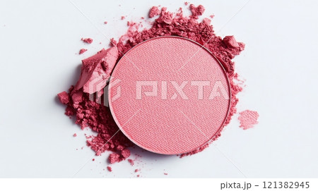 A vibrant pink blush powder is shown in a circular compact, surrounded by loose powder on a clean white surface, illustrating a beautiful blend of color and texture ideal for cosmetic application. 121382945