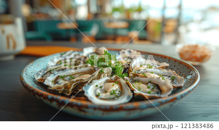 A plate of freshly shucked oysters garnished with herbs, presented in a vibrant coastal dining atmosphere. 121383486