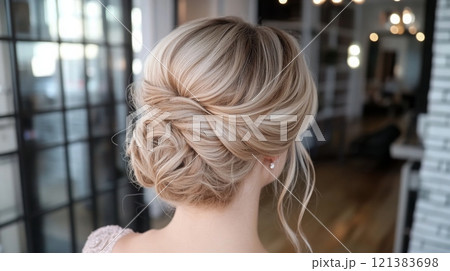 A beautiful updo hairstyle showcases soft waves and elegant twists, perfect for a bride 121383698