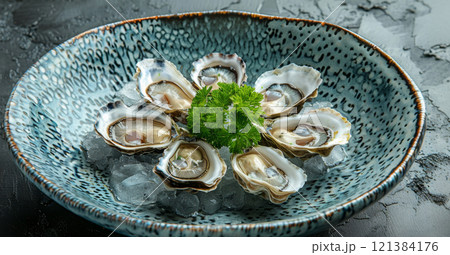 A plate of fresh oysters arranged beautifully on ice, topped with a sprig of parsley, ready for enjoyment. 121384176