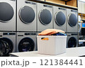 Still life shot of basket full of clean and fresh clothes on folding table in self service laundry with professional washing machines, copy space 121384441