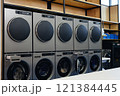 Double row of professional washing machines and coin operated clothes dryers at self service laundromat, copy space 121384445