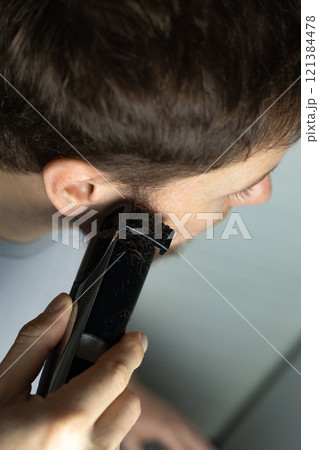 A man trims his beard with a trimmer. An electric razor trimming a beard. Beard care at home. 121384478