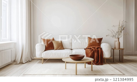 A cozy living room features a white sofa adorned with orange and brown pillows, a soft throw, and a simple coffee table 121384995