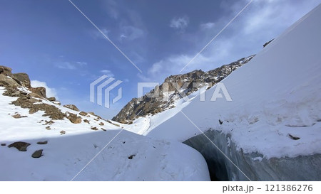 Rocky peak of snow-capped mountain against blue sky 121386276