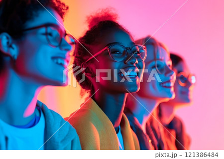 Diverse group of smiling young people in vibrant colorful light setting Diverse group of smiling young people in vibrant colorful light setting 121386484