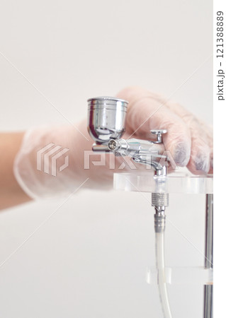 Gloved hand adjusting airbrush equipment for precision spray painting in profess Gloved hand adjusting airbrush equipment for precision spray painting in profess 121388889