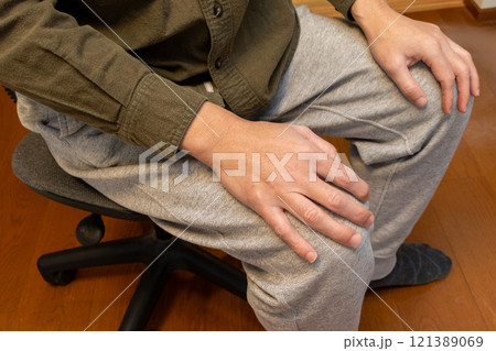 両手を膝の上に置いてイスに座る人物 121389069
