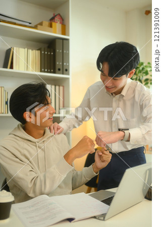 Supportive tutor congratulating a student with fist bump, celebrating progress during a lesson Supportive tutor congratulating a student with fist bump, celebrating progress during a lesson 121391009