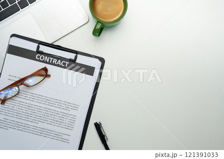 Close up of contract on clipboard, glasses, a cup of coffee and laptop on organized workspace 121391033