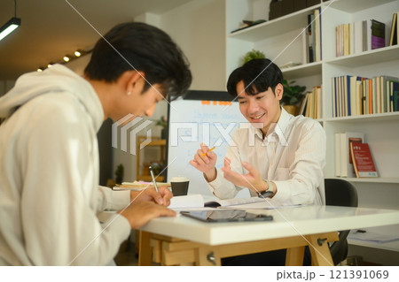 Tutor and student sharing ideas and discussing study materials during a home tutoring session Tutor and student sharing ideas and discussing study materials during a home tutoring session 121391069