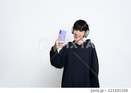 Cheerful young man in modern headphones using mobile phone on a white background 121391109