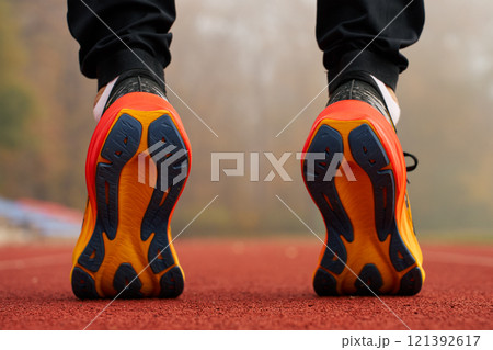 Runner wearing modern sport shoes standing on track surface Runner wearing modern sport shoes standing on track surface 121392617