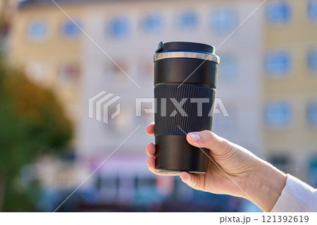 Woman holding reusable coffee cup outdoors in autumn Woman holding reusable coffee cup outdoors in autumn 121392619