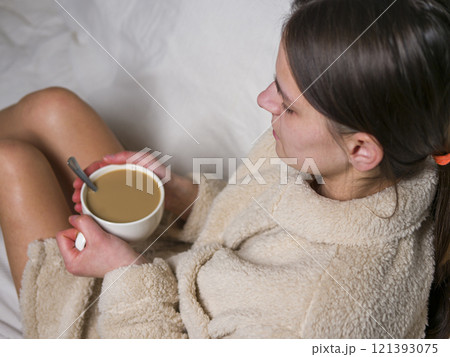 Young woman enjoying tranquil morning in her bathrobe with cup of coffee and sugar 121393075