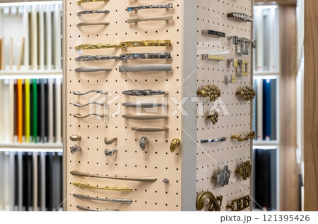 Display of assorted cabinet handles and knobs on pegboard. Interior design and hardware selection. 121395426