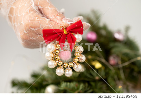 Elegant christmas ornament with red bow and pearls against festive tree background Elegant christmas ornament with red bow and pearls against festive tree background 121395459
