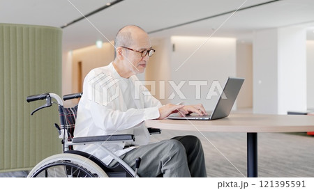 パソコンを操作する車椅子の高齢者 121395591