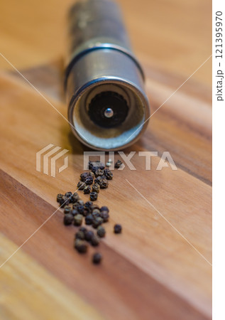 Pepper Grinder with Scattered Peppercorns on wooden background . High quality photo 121395970