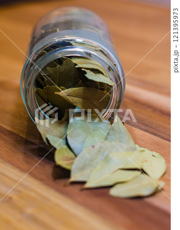Bay Leaves Spilling from a Glass Jar on wooden background . High quality photo 121395973