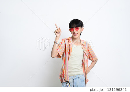 Confident young man wearing sunglasses pointing fingers at copy space over white background 121396241
