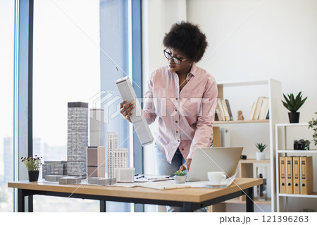 African American female architect in office designing model of modern city with focus and creativity, showcasing expertise and passion for urban development. African American female architect in office designing model of modern city with focus and creativity, showcasing expertise and passion for urban development. 121396263