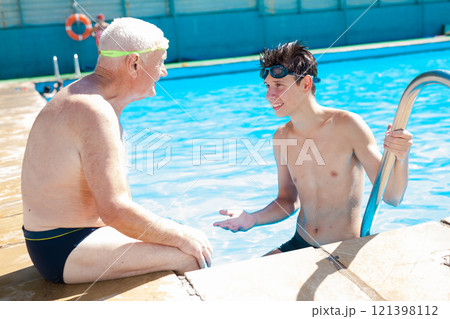 Sports grandfather and grandson communicate in swimming pool 121398112