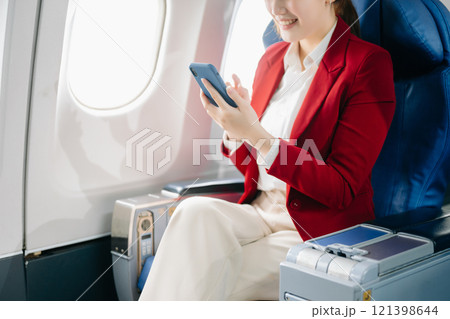 Young Asian executive excels in first class, multitasking with digital tablet, laptop and smartphone. Travel in style, work 121398644