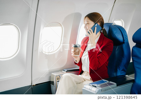 Young Asian executive excels in first class, multitasking with digital tablet, laptop and smartphone. Travel in style, work 121398645