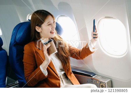 Portrait of a successful Asian businesswoman or entrepreneur in a formal suit on an airplane sitting in business class 121398805