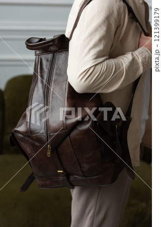 A man posing, with a leather brown backpack 121399179