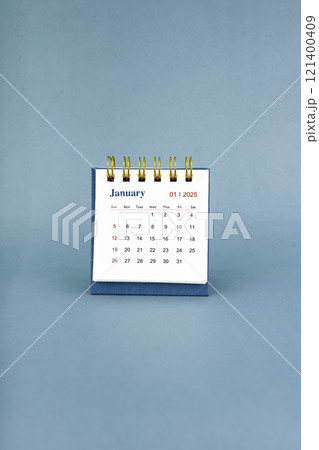 January 2025 white desk calendar on blue background. 121400409