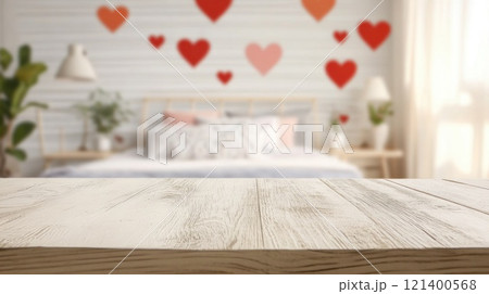 Empty white wooden tabletop on blurred background of bedroom decorated for Valentine's Day with red hearts 121400568