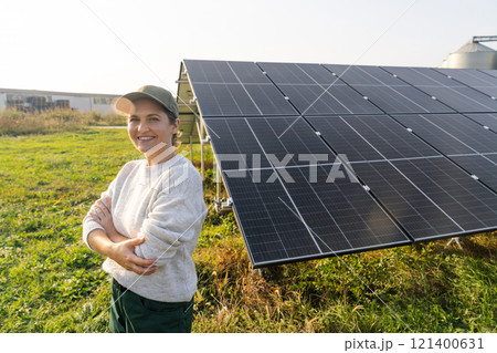 Female farmer on a modern farm using solar panels. Agricultural silos in the background. Female farmer on a modern farm using solar panels. Agricultural silos in the background. 121400631