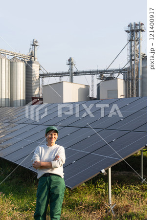 Female farmer with digital tablet on a modern farm using solar panels. Agricultural silos in the background Female farmer with digital tablet on a modern farm using solar panels. Agricultural silos in the background 121400917