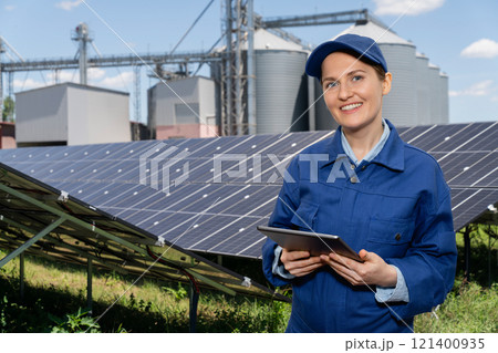 Female farmer with digital tablet on a modern farm using solar panels. 121400935