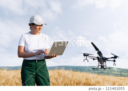 Woman farmer controls drone sprayer with a laptop. Smart farming and precision agriculture Woman farmer controls drone sprayer with a laptop. Smart farming and precision agriculture 121401055