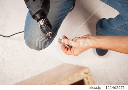 A man holds a screw and a drill in his hand A man holds a screw and a drill in his hand 121402973