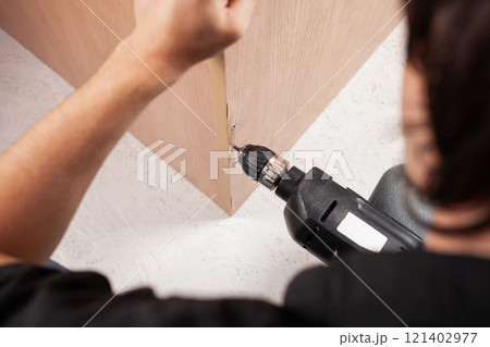 Man twists screw into cupboard 121402977